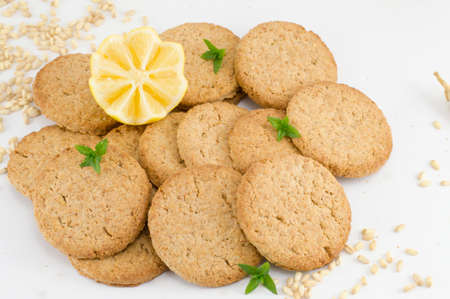 Integral cookies and decorated lemon on white background with wheat and seeds spread all around