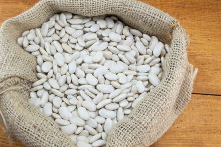 Natural white beans in a bag on a wooden tableの写真素材