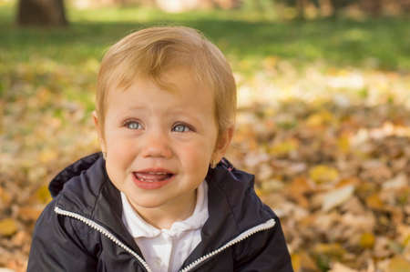 Portrait of a sweet one year old baby girl in a park on a autumn day