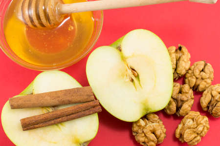 Fresh walnuts, natural honey, cinnamon and apples on red background. Healthy dessertの写真素材