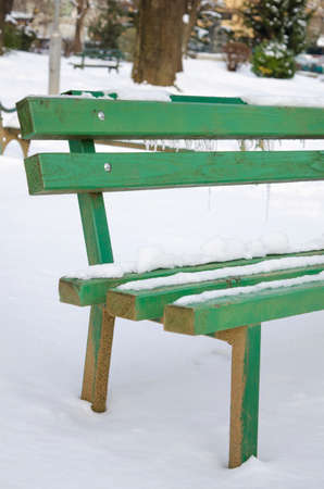 Snow and ice covered bench in a parkの写真素材
