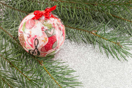 Decoupage decorated Christmas ornament and fir tree on shiny backgroundの写真素材
