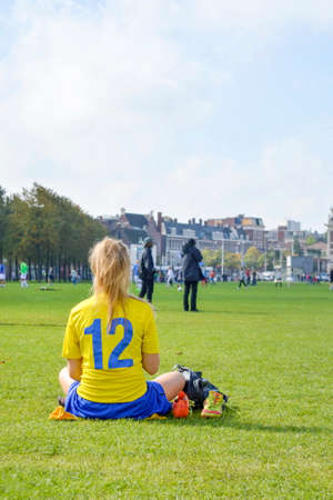 Girl on a break from a soccer game sitting in a parkの写真素材