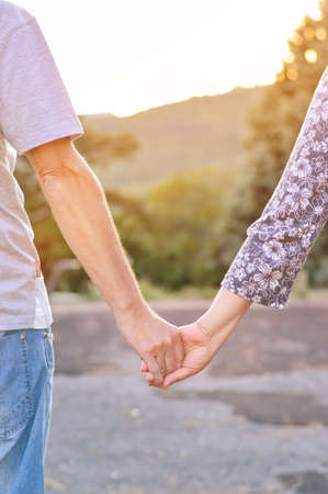 Couple holding hands in the park facing sunsetの写真素材