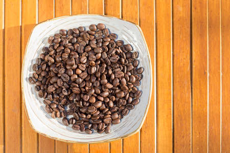 Coffee beans in a plate placed on a wooden tableの写真素材