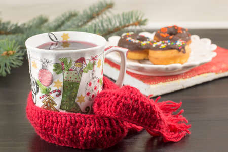 Tee in a decoupage decorated Christmas teacup and homemade donuts on a plateの写真素材
