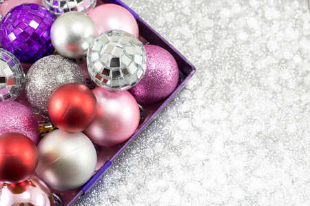 Colorful Christmas ornaments in a bowl against shiny silver backgroundの写真素材