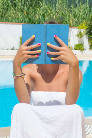 Young girl hat reading by the poolの写真素材
