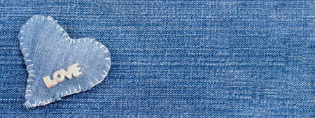 Denim heart with the word love on it on Denim background.