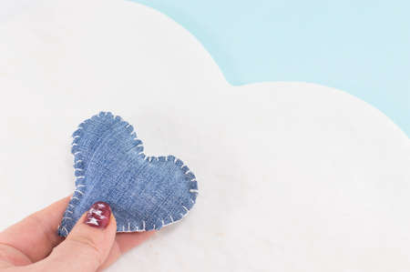 denim heart in woman's hands against a cloud designの写真素材