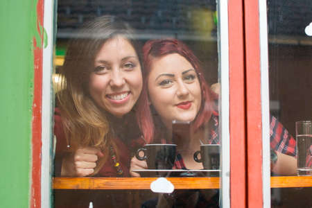 two girlfriends looking at the window of a cafeの写真素材
