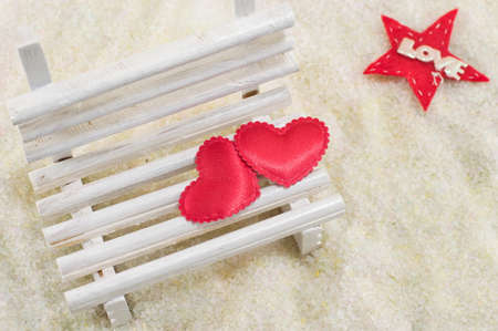 Two hearts on a miniature wooden bench with a love noteの写真素材