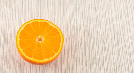 Half of an orange on white wooden tableの写真素材
