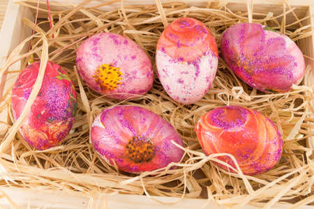 Decoupage decorated Easter eggs in a wooden box filled with straw