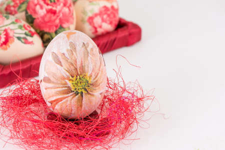 Decoupage decorated Easter egg on red strawの写真素材