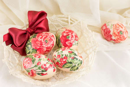Decoupage decorated Easter eggs in a basket against silky backgroundの写真素材