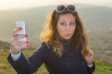 Girl taking a selfie on a hiking trip at sunsetの写真素材