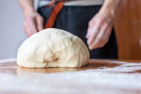 Male baker makes bread on the tableの写真素材