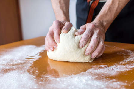 Male baker makes bread on the tableの写真素材