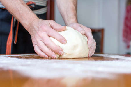 Male baker makes bread on the tableの写真素材
