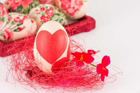Decoupage decorated Easter egg on red strawの写真素材
