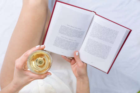 Woman having a glass of white wine in bedの写真素材