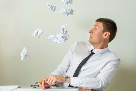 Crumpled papers flying into young businessman faceの写真素材