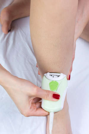 Girl epilates her leg with an epilator at home