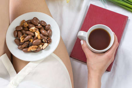 Woman haing a morning snack and tea in bedの写真素材