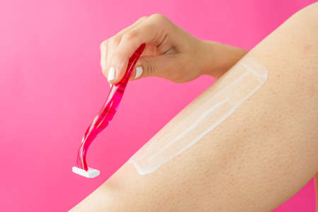 woman shaving her leg with red shaverの写真素材