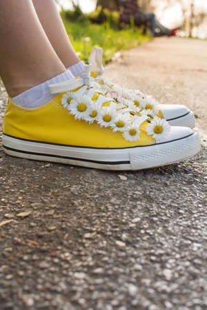 Yellow sneakers decorated with daisies in the parkの写真素材