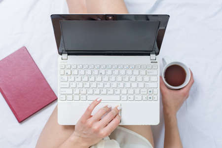 Woman working on a notebook while in bed