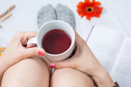 Woman holding a cup of tea in bedの写真素材