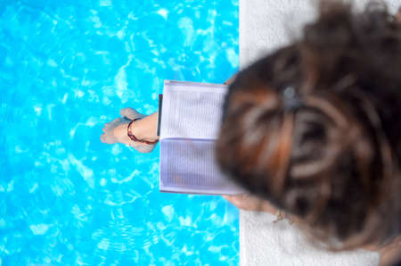 Girl reading by the swimming pool