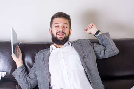 Sleepy businessman stretching with a tablet deviceの写真素材