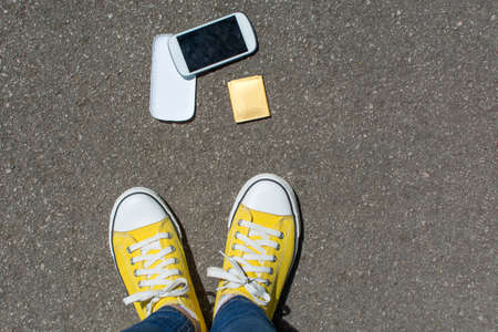 Disassembled smartphone on the ground in front of person. First person point of view