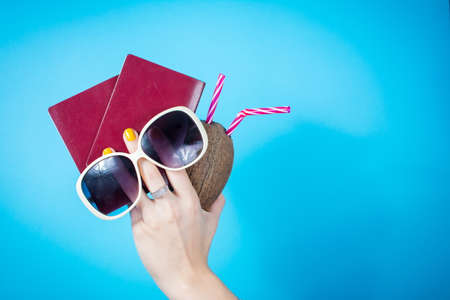 Womans hand holding a two passports and summer accessories against blue backgroundの写真素材