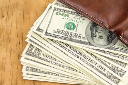 Leather wallet with dollar bills falling out