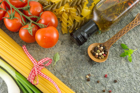Uncooked spaghetti pasta with vegetables a stone tableの写真素材