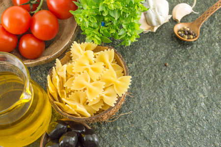 Uncooked pasta in a bowl with vegetables and spicesの写真素材