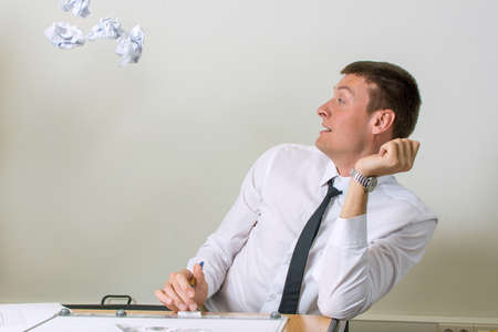 Crumpled papers flying into young businessman faceの写真素材