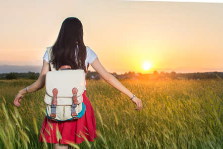Young woman in a wheat field at sunsetの写真素材
