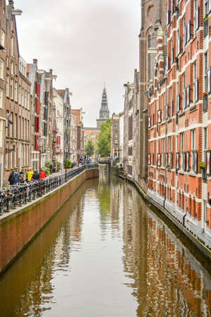 AMSTERDAM - SEPTEMBER 17, 2015: View at the famous clock tower of the Zuiderkerk thro Amsterdam canal with some tourist passing during dayのeditorial素材