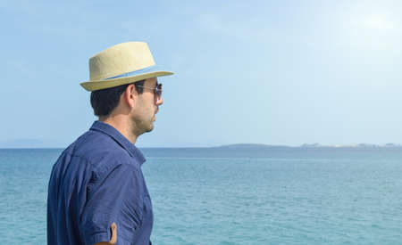 Man in blue shirt looking at the horizon at seasideの写真素材