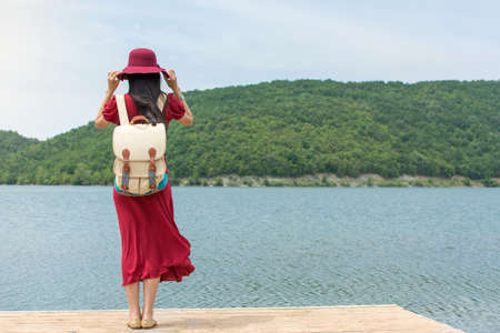 Fashionable woman standing in front of a lake aloneの写真素材