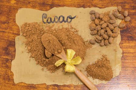 Cacao powder, wooden spoon and candy on dark cooking paperの写真素材