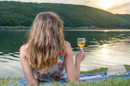 Woman having a glass of wine by the lake