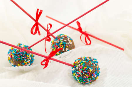 Cake pops on a table covered with white silk fabric