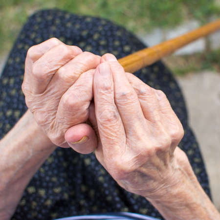 Old woman hands holding a walking cane outdoorsの写真素材
