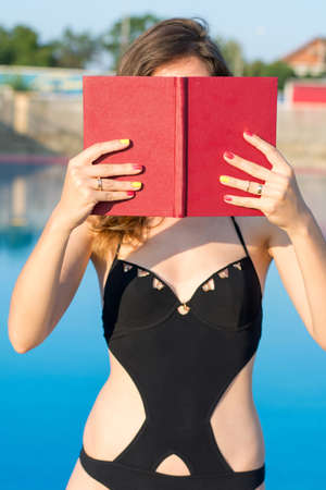 Girl in swimsuit reading a book by the poolの写真素材